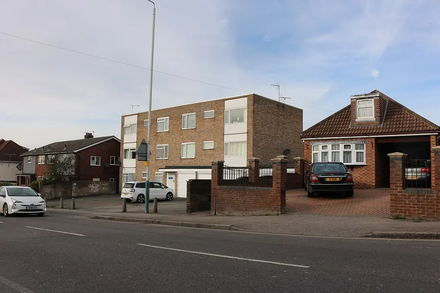 Block of flats next to a bungalow with gated parking on Upminster Road in Hornchurch