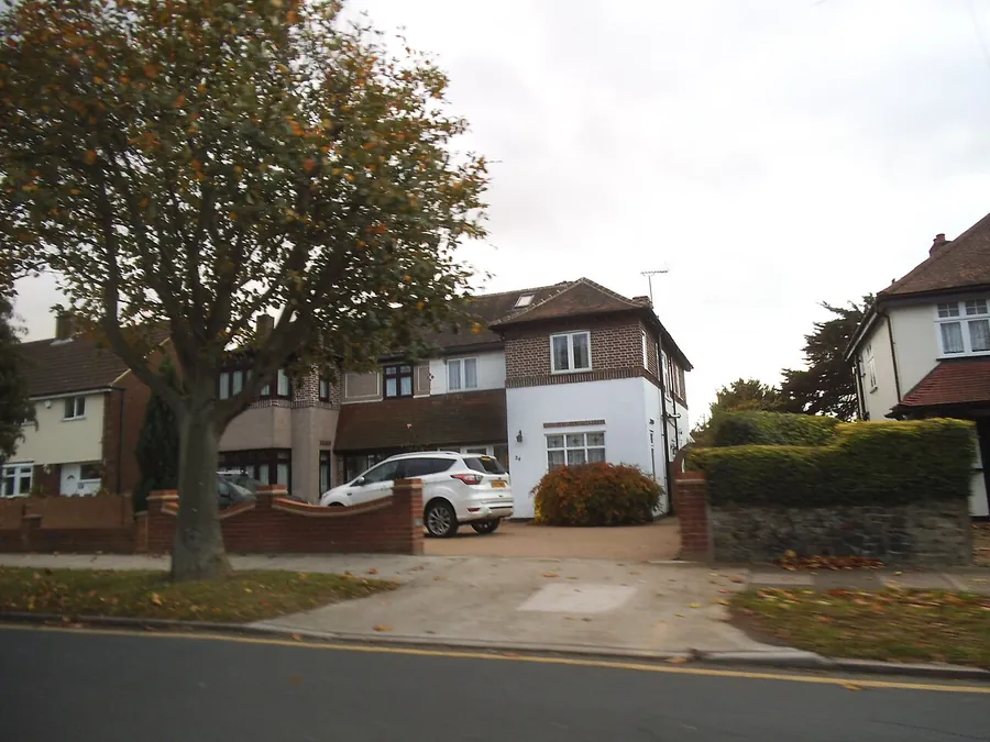 Semi-detached house on Ravenscourt Grove in Hornchurch with a clipped hedge, low brick wall and a car on the block paved drive