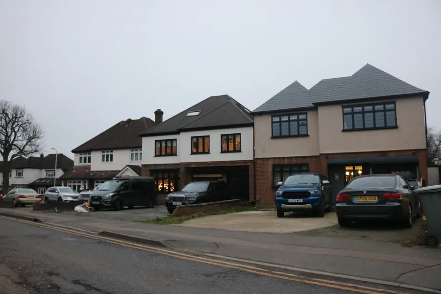 Large detached houses on Hall Lane in Upminster with wide frontages and several cars parked off the road