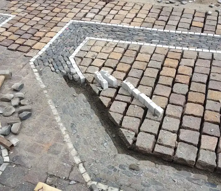 Block paving edge course being set on a concrete bed at the side of a driveway