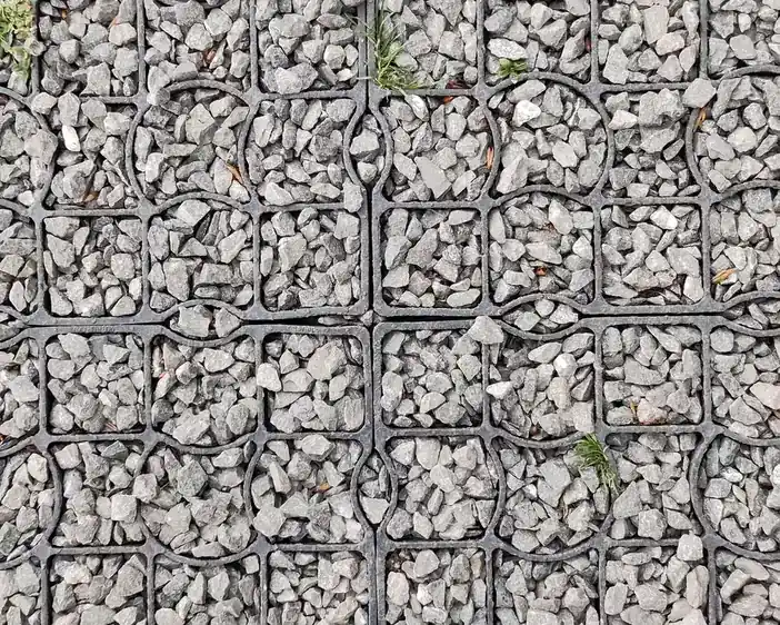 Close-up of angular gravel settled into a honeycomb stabilising grid on a driveway
