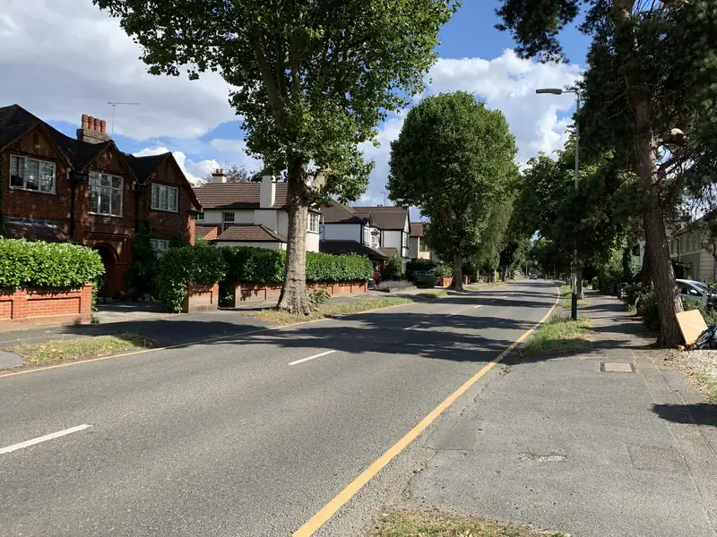 Arts and Crafts style detached houses with hedged front gardens on a tree-lined road in Gidea Park, Romford